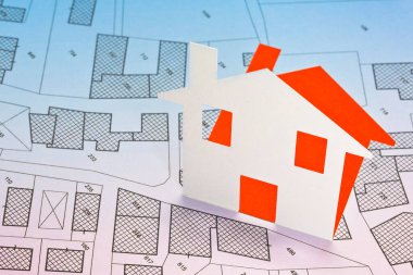 Karton ev ve hayali kadastro haritasıyla emlak kavramı, binalar, arazi paketleri ve kentsel varış noktaları göstergeleriyle Genel Şehir Planı
