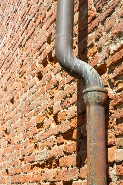 Old rusty copper and cast iron downpipe against a brick wall