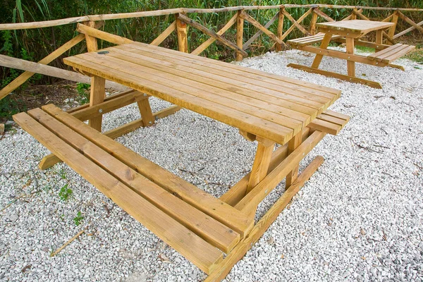 Yeni ahşap piknik masası beyaz çakıl zemini olan bir parkta.