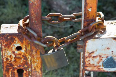 Eski hasarlı ve paslı bir fabrikanın asma kilitle kapatılmış kapısı.