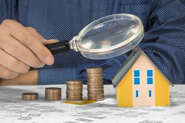 Binalar için emlak vergisi - Küçük bir ev modeli, avro sikkeleri grubu ve büyüteç - emlak değeri artışı konsepti