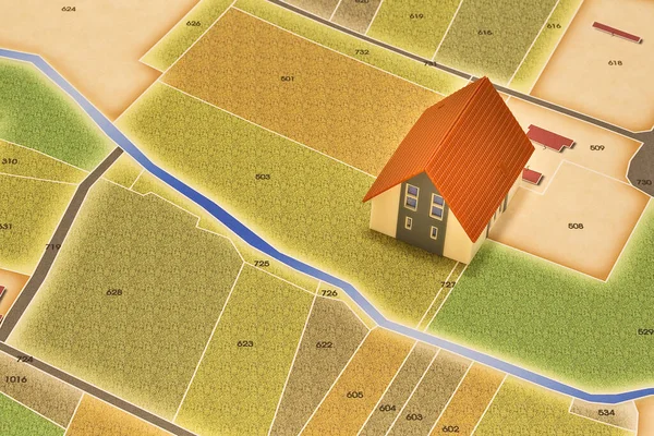 New home and free vacant land for building activity in rural land - Construction industry concept with a model of rural building and imaginary cadastral map