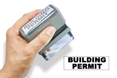 Buildings Permit about building activity and construction industry - concept with hand and plastic stamp with text on white background
