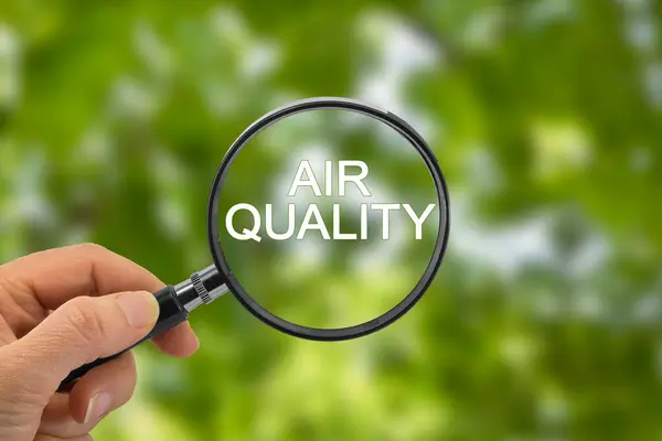 Hava Kalitesi kavramı, yeşil çözünmüş bir manzaraya karşı, üzerinde yazılı metin bulunan bir büyüteç tutuyor..