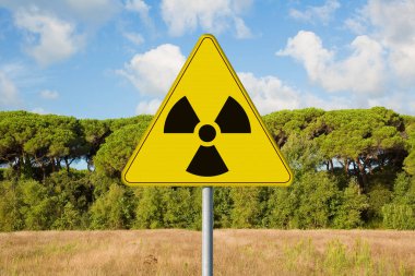 RADON GAS tarafından radyoaktif kirlenme tehlikesi - bir bina arsasına ve inşaat için boş araziye karşı yol tabelasında radyoaktivitenin uyarı sembolü olan kavram