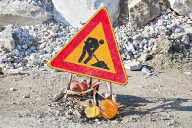 Çakıl ve taşlı bir inşaat alanında yol çalışması tabelası.