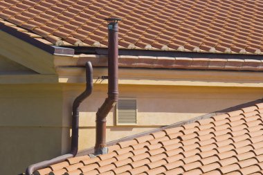 Çatıda bakır borusu olan metal baca, yoğunlaştırıcı kazanların çatısında egzoz borusu.