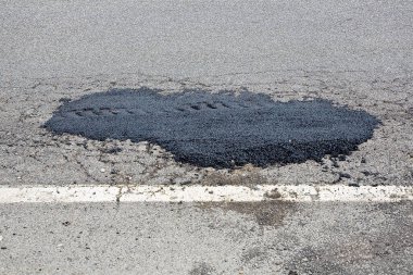 Eski hasarlı ve yıpranmış asfalt yolu. Çukuru yeni bitumenlerle dolu.