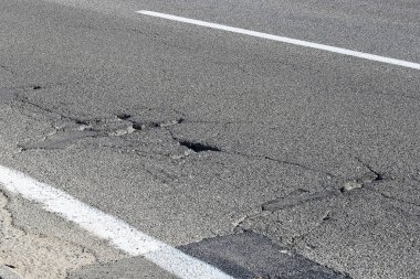 Motorlu taşıtların geçişi için tehlikeli çukurları olan tehlikeli asfalt yolu..