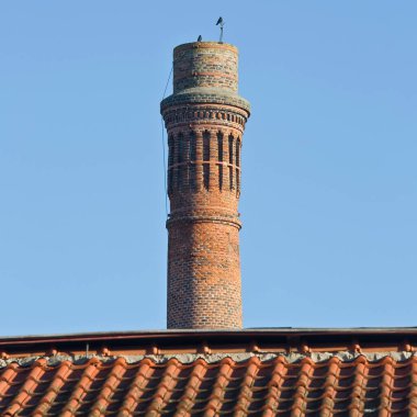 Eski bir imalat endüstrisinin tuğla bacası açık gökyüzünde dumansız bir şekilde izole edilmiş.