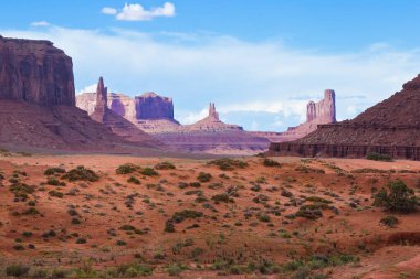 The Monument Valley in Utah Arizona state with the red earth desert in the foreground - The valley is considered sacred by the Navajo Nation - USA clipart