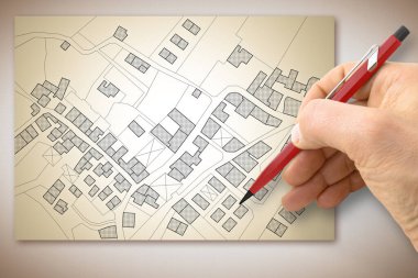 Bir masanın üzerinde binaların, tarlaların, yolların ve arazi parsellerinin olduğu hayali bir kadastro haritası çizmek - kavram resmi