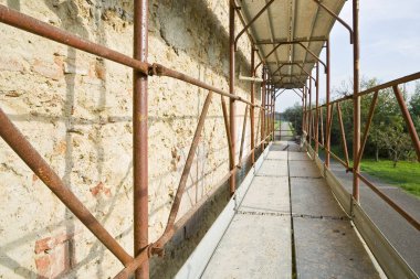 Eski Plaster 'ı bir taştan ve BRICK WALL' dan çıkarmak - Şelalelerden korunmak için güvenlik metali iskelesi olan bir inşaat alanında çalışmak