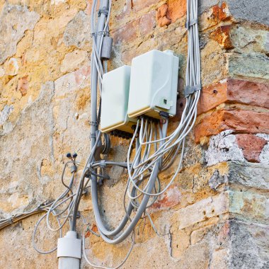 Telefon kabloları kabaca plastik bağlantı kutusuyla eski bir alçı duvara monte edilmiş..