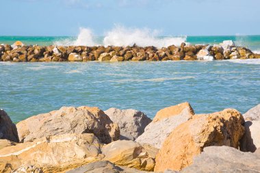 Kıyı şeridini doğal deniz fırtınası koruma barajı ile savunurken kıyı şeridi boyunca deniz dalgalarını koruyan taş bloklar da var.