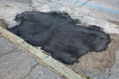 Motorlu taşıtların geçişi için tehlikeli çukurları olan tehlikeli asfalt çukurları olan eski ve yıpranmış asfalt yol yeni ziftle dolu çukurlu eski hasarlı ve yıpranmış asfalt yol