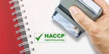 Elinde HACCP sertifikalı bir plastik pul (Tehlikeli Analizler ve Kritik Kontrol Noktaları) - Gıda endüstrisinde Gıda Güvenliği ve Kalite Kontrolü - bulanık elli ve yer kopyalı konsept 