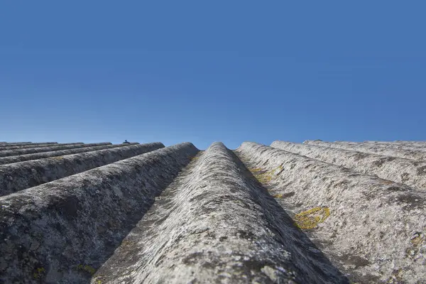 Eski, eğri büğrü asbest panellerden yapılmış çatı - binalarda ve inşaat sektöründe tehlikeli malzemeler