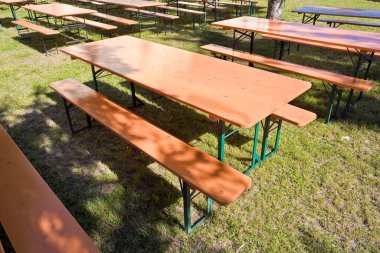 Ağaçlı bir parktaki yeşil çayır üzerinde ahşap piknik masası.