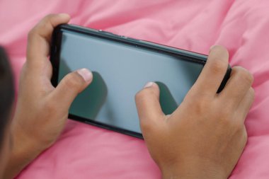 Boş siyah ekranlı akıllı telefon kullanan bir çocuğun yakın çekimi