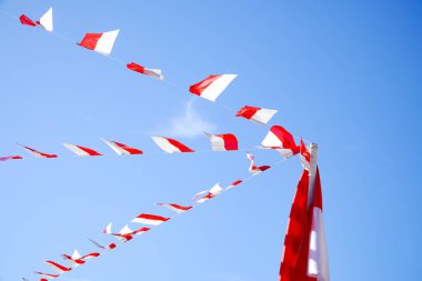Kırmızı ve beyaz süslemeler, Endonezya 'nın Bağımsızlık Günü' nü kutlamak için mavi gökyüzünün arka planında asılı..