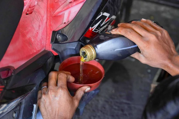 The process of pouring new oil into the motorcycle engine. Motorcycle service. Mechanics pouring the engine oil motorbike, doing regular maintenance
