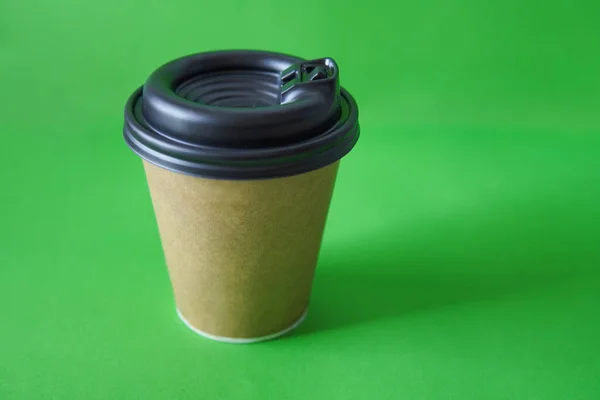 coffee to go in a disposable cup on a green background, you can place text, kraft paper cup. Takeaway paper coffee cup