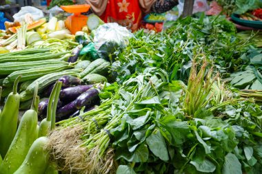 Asya 'da taze sebze ve otlarla dolu bir tezgah. Sokak yemeği. Geleneksel yerel gıda pazarı. çeşitli taze sebzeler satılıyor.