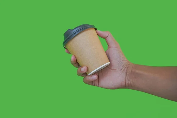 hand holding a Takeaway paper coffee cup. coffee to go in a disposable cup on a green background, you can place text or logo, kraft paper cup.