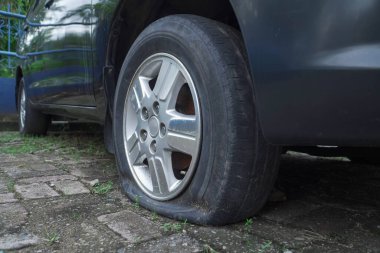 Otoparkta lastiği patlamış, tuğlalarla kaplanmış. Terk edilmiş gibi görünüyor.