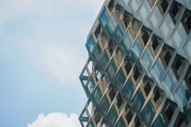 Modern mimari detaylar. Geometrik desenli modern cam cephe. Geometrik tasarımın modern ve çağdaş mimarisi. Kopyalama alanı olan mavi gökyüzü arkaplanı