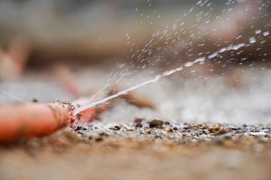 Hortumdaki delikten su sızıyor. Lastik tüpten yere su sızıntısı.