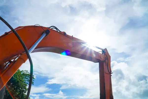 Backlit excavator on an industrial site against the background of the blue sky. Construction machinery for earthworks. Hydraulic piston system. construction heavy industry detail