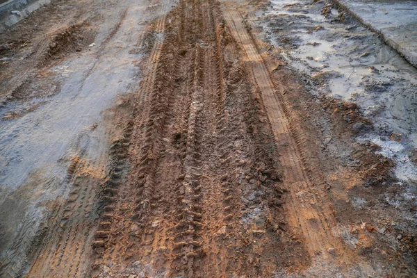 Deep tires tracks on the road covered by wet muddy sand
