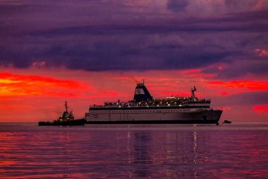 Vlore, Arnavutluk - 5 Eylül 2022: Büyük yolcu feribot gemisi Logos Hope, Vlore şehir limanında günbatımı arka planında. Adriyatik Denizi 'nde harika bir gün batımı. Seyahat konsepti arka planı.