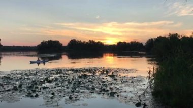 two people in kayak on lake in sunset light