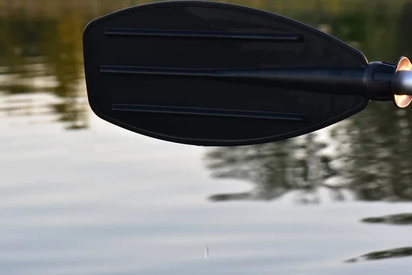 黑色桨在水里 水花在金色的背面落日的光芒中 — 图库照片