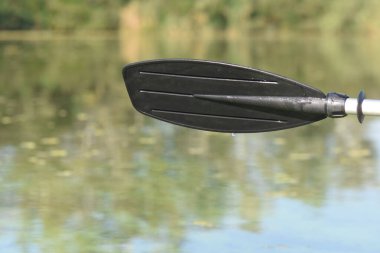 Yeşil nehir suyunda siyah kürek üstüne su sıçrıyor.