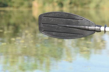 Yeşil nehir suyunda siyah kürek üstüne su sıçrıyor.