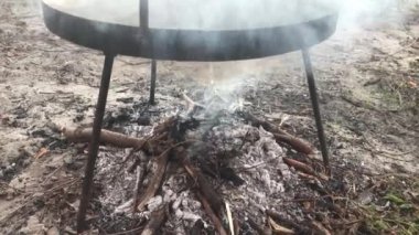 Kızartma tavasının altında dumanlı kamp ateşi 