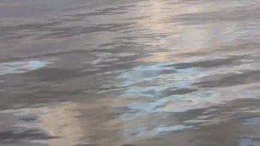 sakin nehir dalgaları arkaplan su yüzeyi renkli dramatik gökyüzünü yansıtıyor