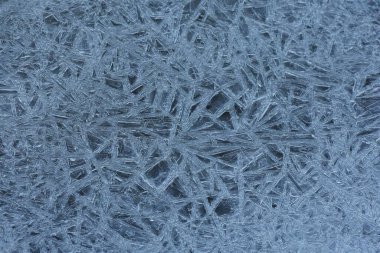 Kışın donmuş bir gölün üzerindeki donuk desen, fotoğrafın yakın çekimi.