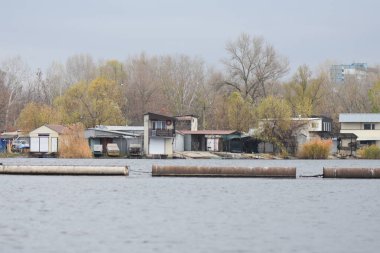 Sonbahar bulutlu bir günde nehrin kıyısında terk edilmiş binalar.