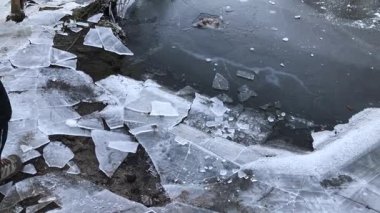 Kırık buz üzerinde yürüyen bir adam nehir sahilinde