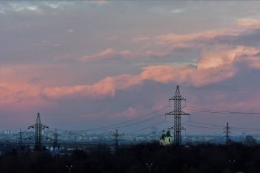 Bulutlar, şehrin üzerinde yüksek voltajlı kuleyle Sunset 'te renkli bulutlar. 