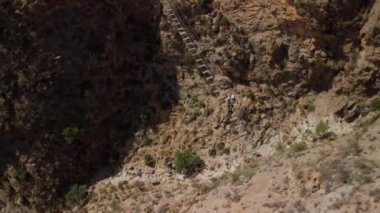 İnsan korkularının üstesinden, asma köprüyü geçerek gelir. Büyük bir genel uçak adamın üzerinde uçar. Köprü, kireçtaşı bir kaya vadisinde yer alır..