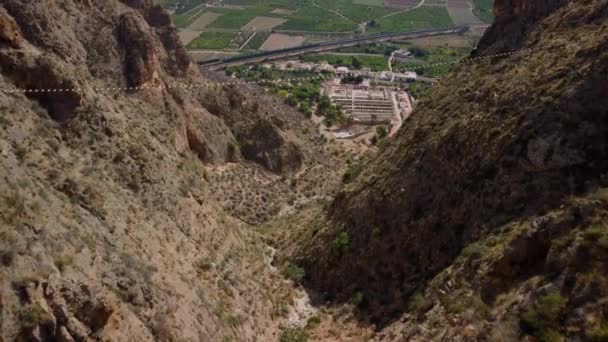 男は谷を渡る吊り橋を渡ることによって彼の恐れを克服する フェラタ経由で石灰岩の山が見えます — ストック動画