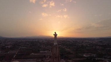 İsa 'nın heykeli ve göğsünden yükselen güneş. Cristo de Monteagudo, Murcia, İspanya. Gün batımında hava videosu.