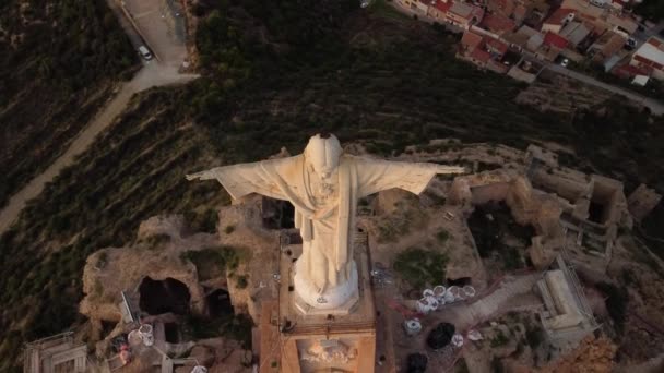スペインのムルシア州モンテナグドのキリスト 小さな町の後ろにキリスト教のシンボルの垂直パンニングの空中ビデオ — ストック動画