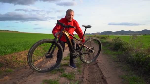 Homem Sênior Levanta Sua Bicicleta Elétrica Com Força Seus Braços — Vídeo de Stock